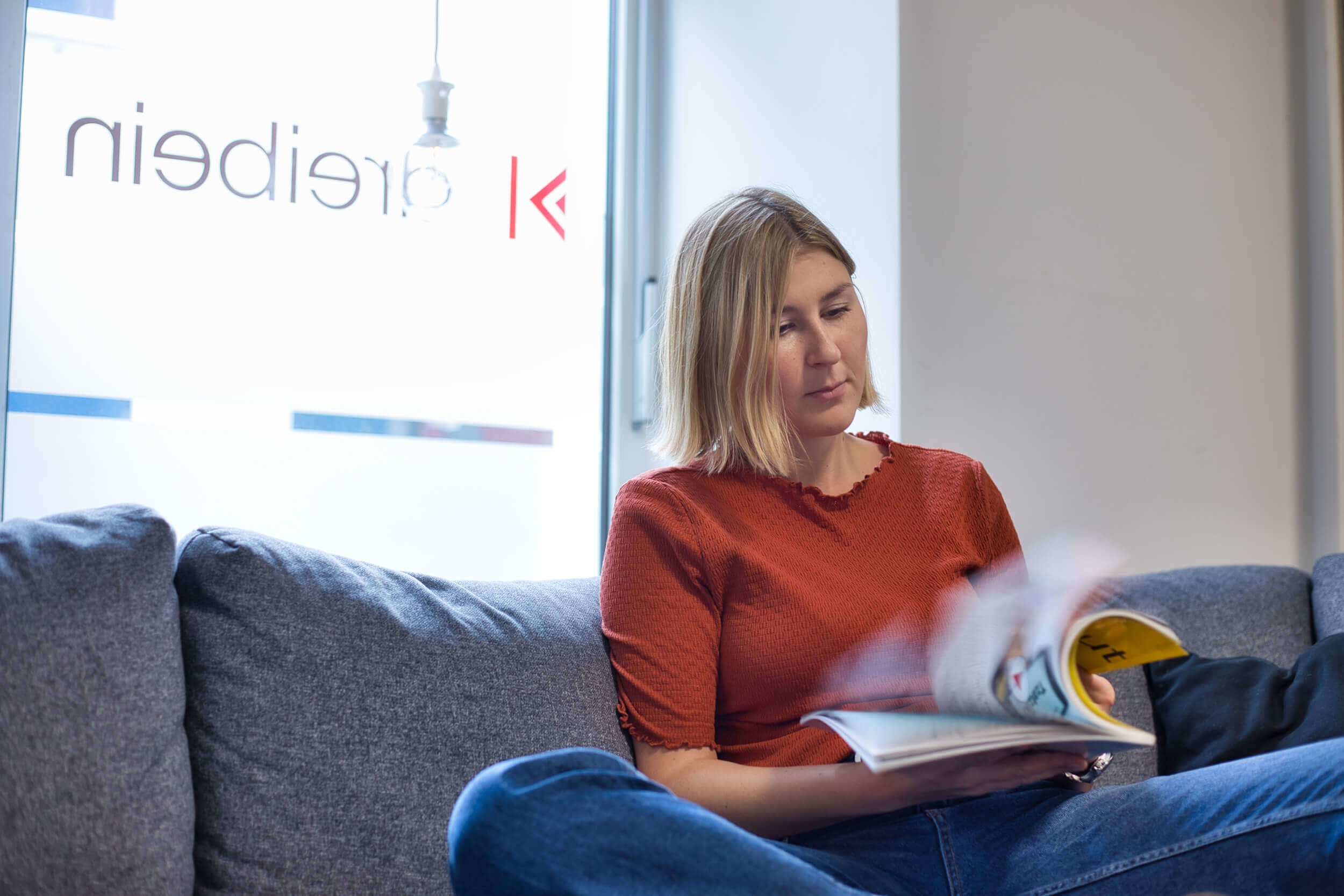 Mitarbeiterin der Agentur Dreibein blättert durch Magazin