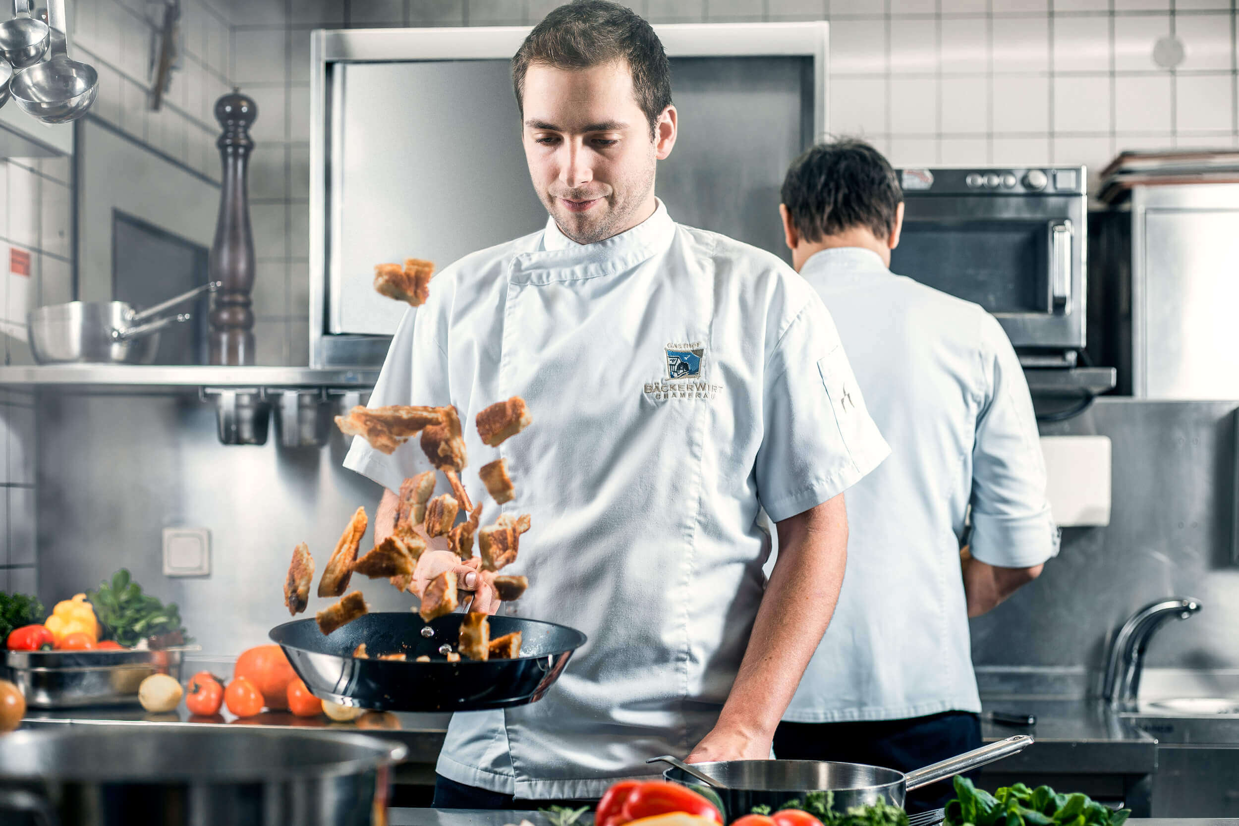 Koch schwingt eine Pfanne in der Küche des Gasthofs Bäckerwirt