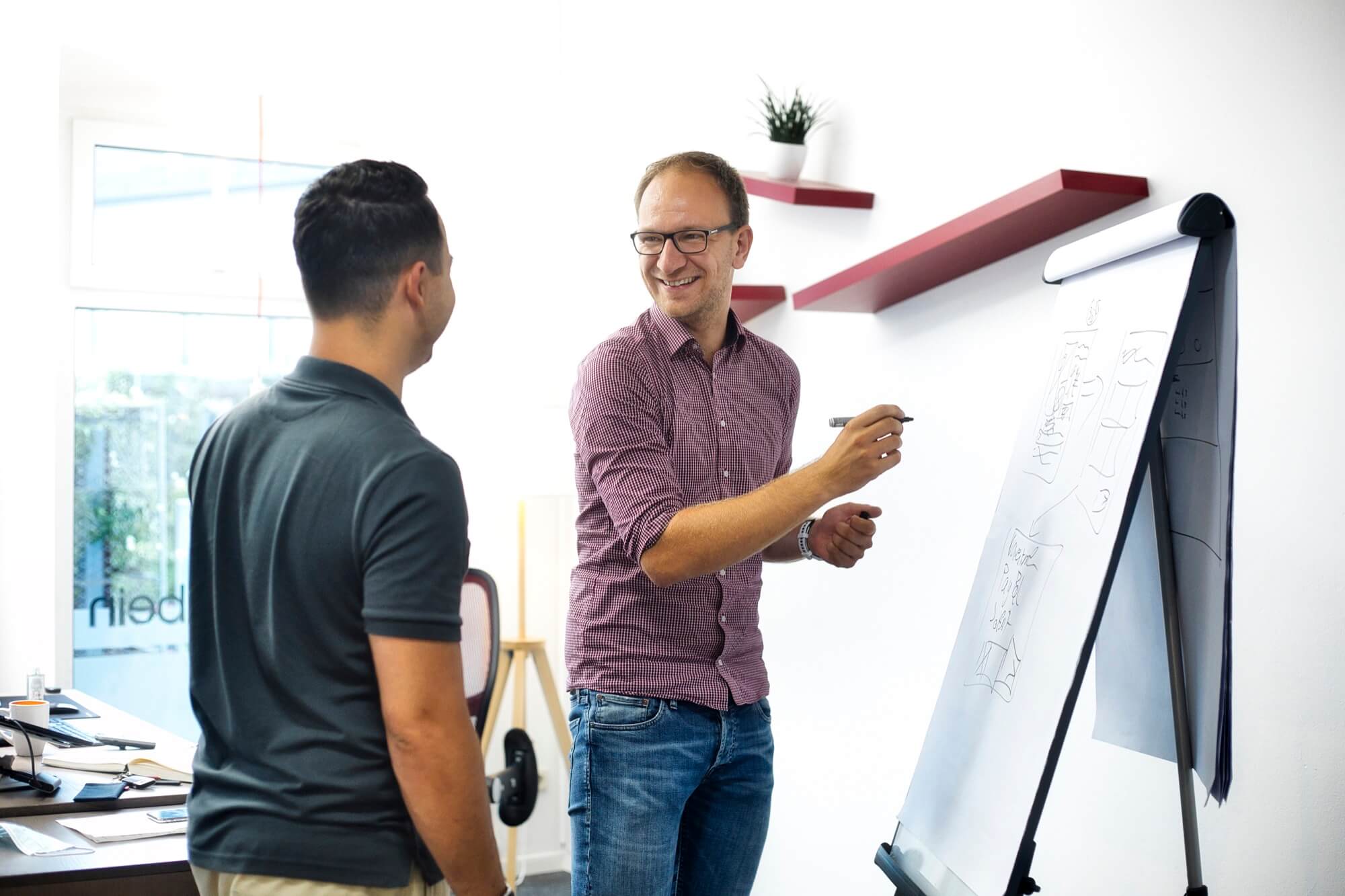Zwei Mitarbeiter planen ein Design an einem Flipchart